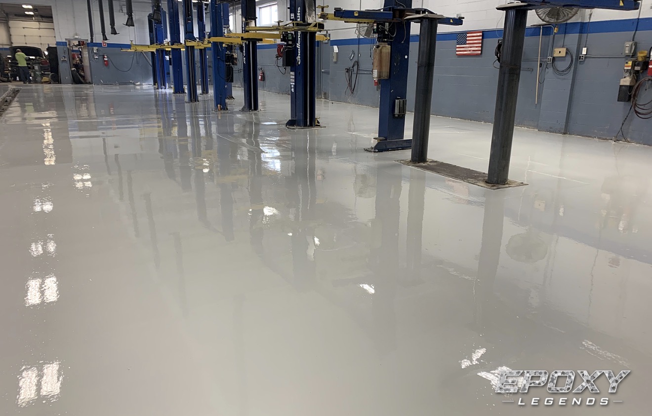 Light gray epoxy floor coating in an auto repair shop with vehicle lifts